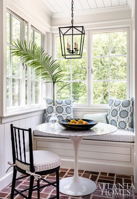 Breakfast nook with marble tulip table, black chair, banquette seating, and large windows