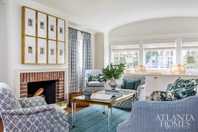 Living room with brick fireplace, patterned armchairs, blue sofa, and Atlanta Homes & Lifestyles