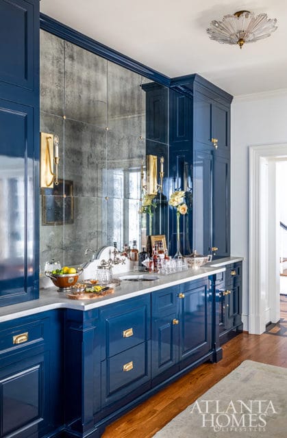 Blue bar with marble countertop and mirrored backsplash.