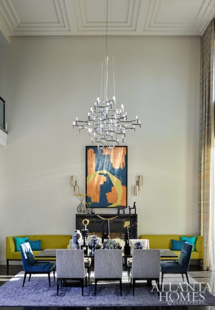 Dining room with gray chairs, yellow sofa, abstract art, and modern chandelier
