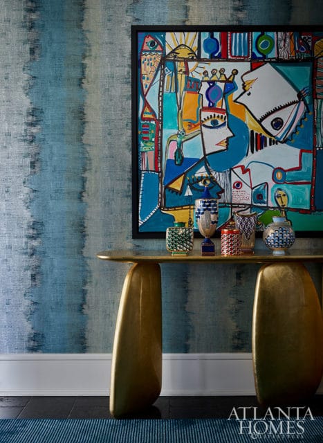 Abstract art above console table with decorative vases and blue striped rug