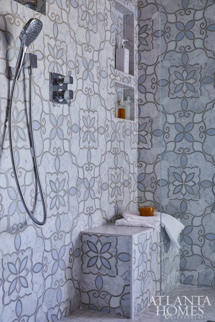 Shower with patterned marble tile, built-in bench, and chrome fixtures.