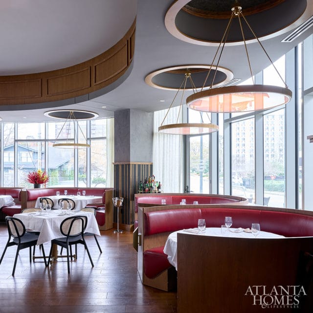 Restaurant dining room with red leather booths, white tablecloths, and modern circular pendant