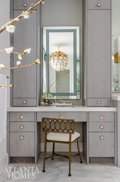 Gray vanity with white countertop, ornate gold chair, and mirrored cabinet