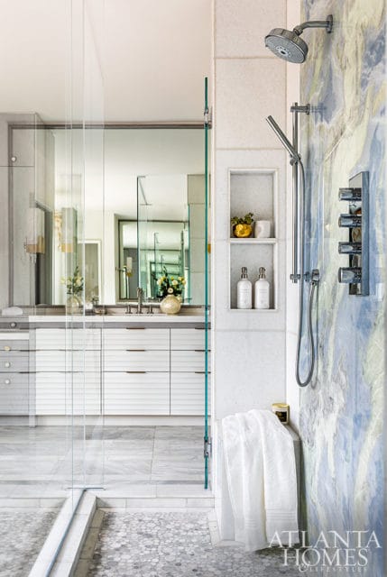 Modern bathroom with blue marble shower, white vanity, and glass shower enclosure.