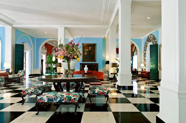 Lobby with black and white checkered floor, blue walls, floral chairs, and large floral arrangement