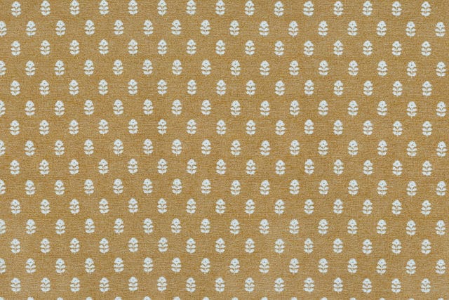 Ochre fabric with a repeating white floral motif pattern