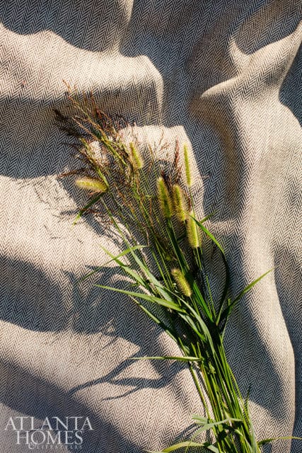 Close-up of a herringbone-patterned fabric with a bouquet of green grass and seed heads.