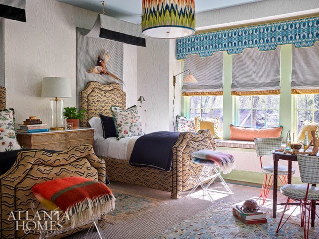 Bedroom with two beds, patterned headboards, botanical print pillows, and a window seat.