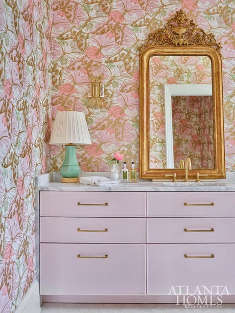 Pink vanity with marble countertop, gold mirror, and butterfly wallpaper
