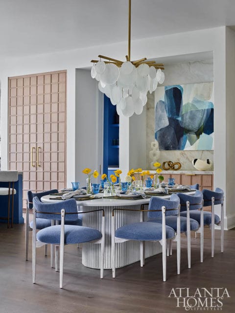 Dining room with oval table, blue upholstered chairs, and capiz shell chandelier