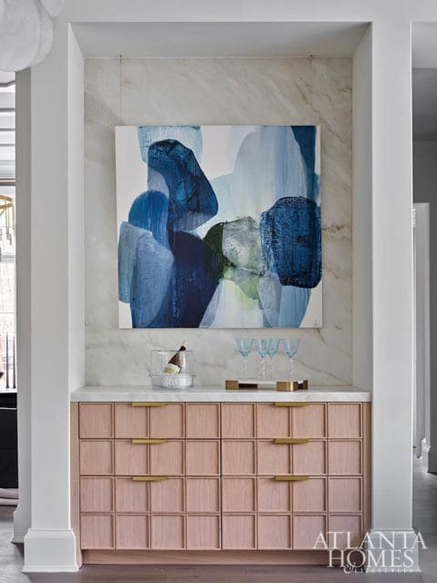 Pink wood cabinet with gold handles, marble countertop, abstract blue art