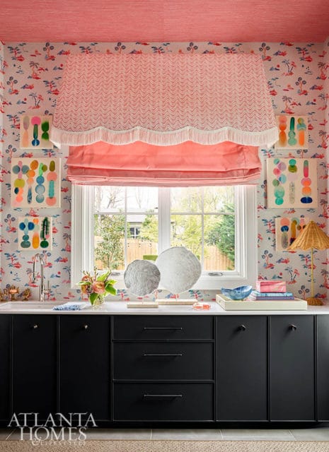 Pink scalloped valance and roman shade over window with tropical wallpaper and abstract art