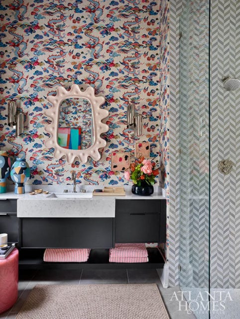 Bathroom with dragon print wallpaper, chevron tile shower, and pink stool.