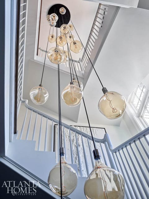 Staircase with a multi-bulb pendant light fixture with clear glass shades.