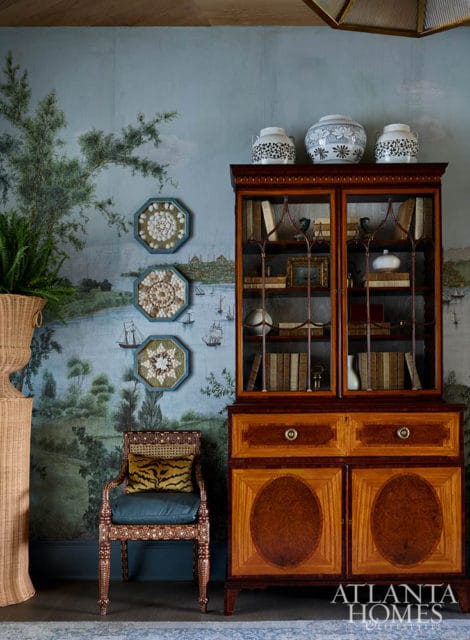 Room with chinoiserie wallpaper, antique cabinet, and decorative shell art.