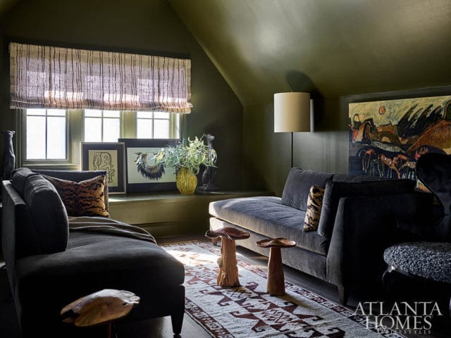 Dark green room with two gray sofas, patterned rug, and abstract art.