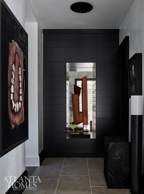 Hallway with dark wood paneling, abstract sculpture, and artwork