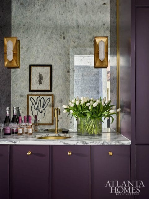 Purple bar cabinets with marble countertop, gold faucet, and white tulips.