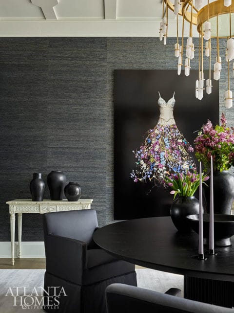 Dark dining room with black table, chairs, and artwork of a dress made of flowers.