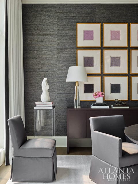 Gray dining chairs, dark wood buffet, and framed abstract art on textured wallpaper.