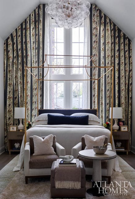Bedroom with gold canopy bed, patterned curtains, and two armchairs.