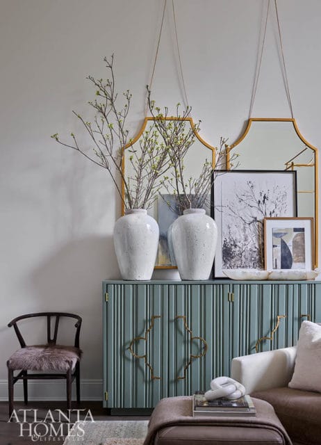 Pale blue cabinet with gold hardware, topped with white vases and artwork.