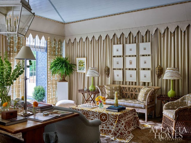 Living room with patterned sofa and chairs, draped curtains, and framed art.