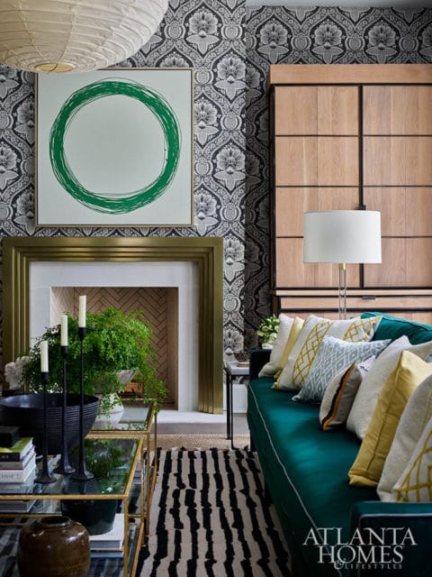 Living room with teal sofa, patterned wallpaper, fireplace, and artwork
