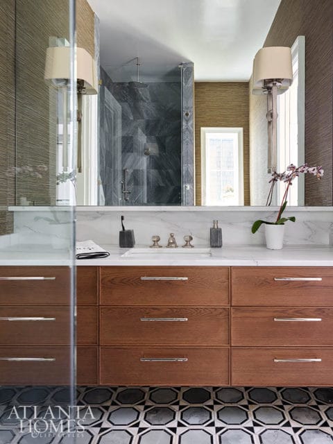 Bathroom with wood vanity, marble countertop, and geometric tile floor.