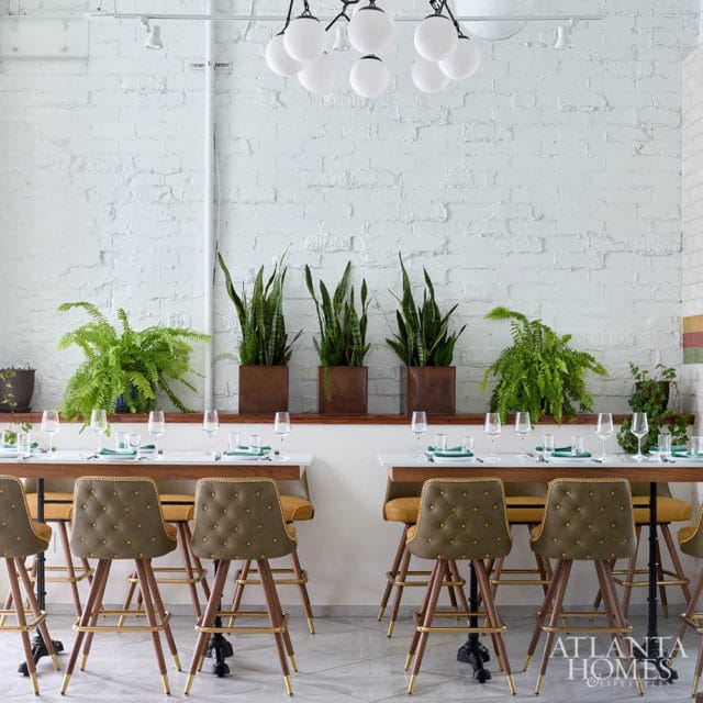 Dining room with white brick walls, tufted bar stools, and snake plants.