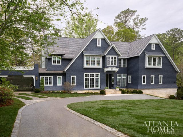 Dark blue shingle-clad house with white trim and stone foundation.