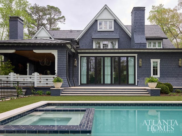 Dark blue shingle-clad house with black-framed doors and windows, and a swimming pool.