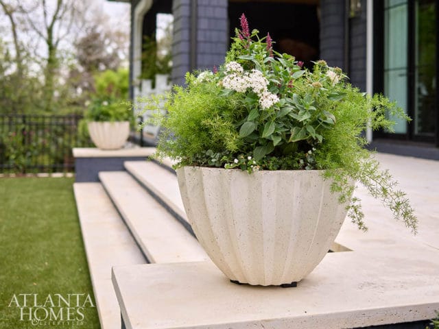 Concrete planter with white and pink flowers and green foliage on stone steps