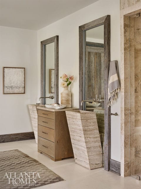 Bathroom with two stone pedestal sinks, wood vanity, and tall mirrors with rustic frames.
