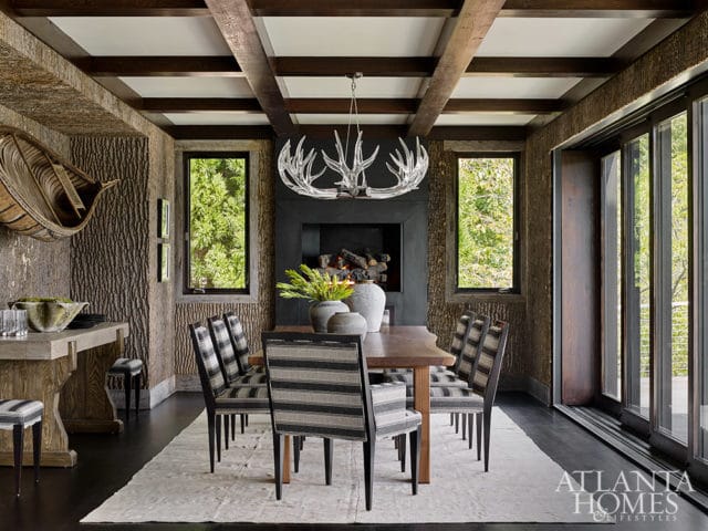 Dining room with wood-paneled walls, antler chandelier, and striped chairs.