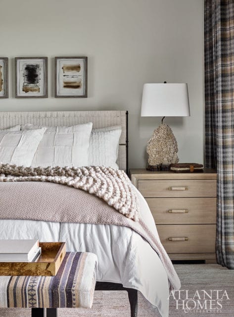 Bedroom with white bedding, textured throw blanket, and abstract art.
