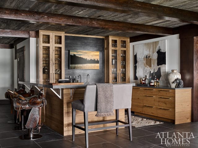 Bar with wood cabinetry, stone countertop, saddle display, and abstract art.