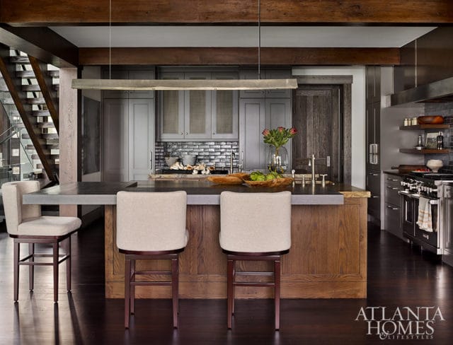 Modern kitchen with gray cabinets, concrete island, and wood accents.