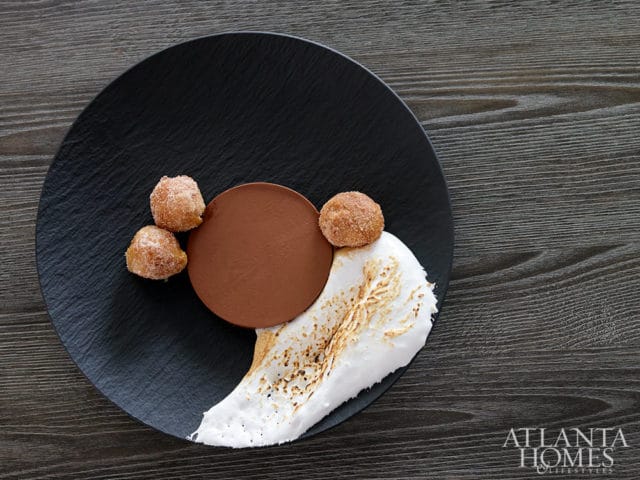 Chocolate dessert with toasted meringue and cinnamon sugar balls on black plate