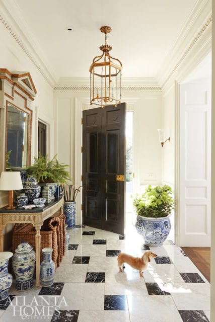 Foyer with black double doors, marble floor, blue and white ginger jars, and a dachshund.