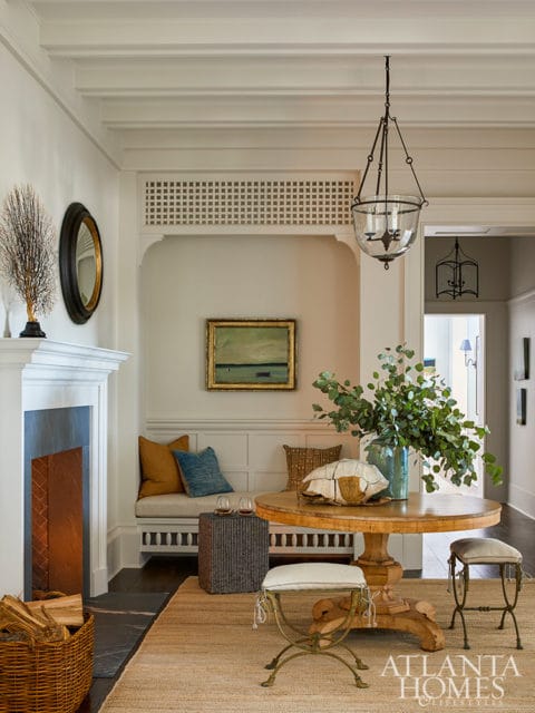 Entryway with fireplace, built-in bench, round wooden table, and Atlanta Homes & Lifestyles logo