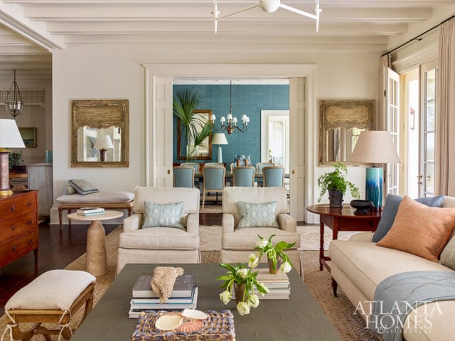 Living room with neutral upholstered chairs and sofa, view into dining room with blue walls and