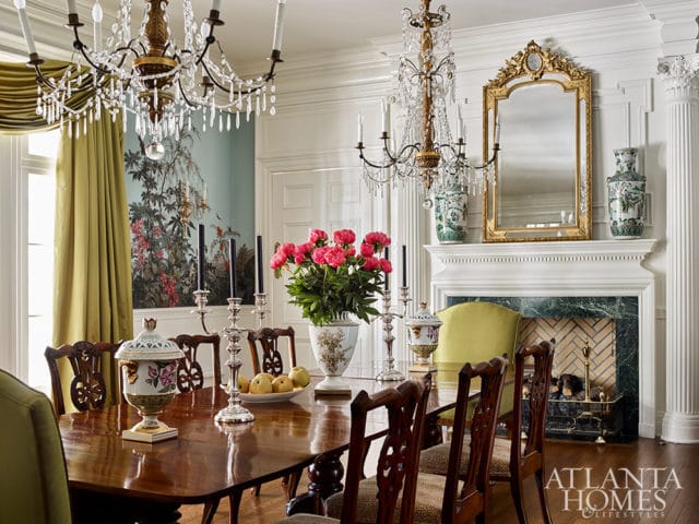 Dining room with dark wood table, floral wallpaper, green curtains, and ornate fireplace