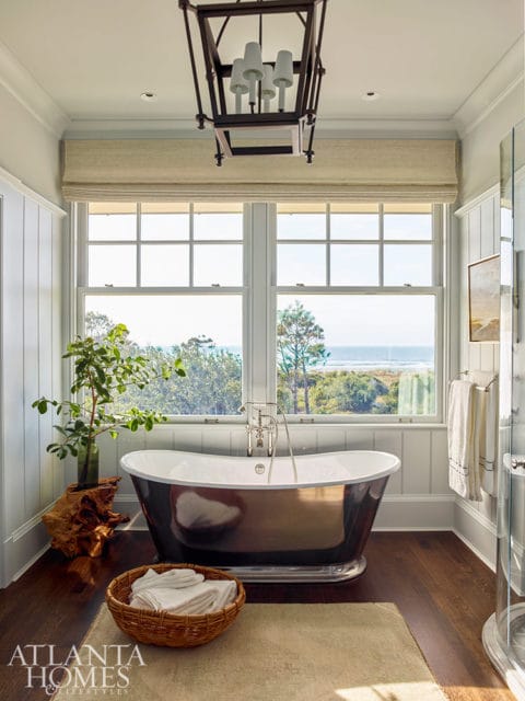 Primary bathroom with dark freestanding tub, wood floors, and ocean view
