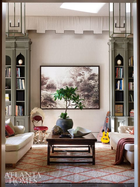 Living room with striped wallpaper, built-in bookshelves, and a large landscape artwork.
