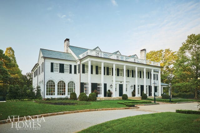 White colonial-style house with a large columned porch and green lawn.