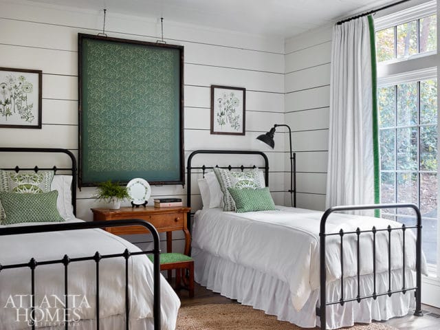 Bedroom with two twin beds, shiplap walls, and botanical prints.