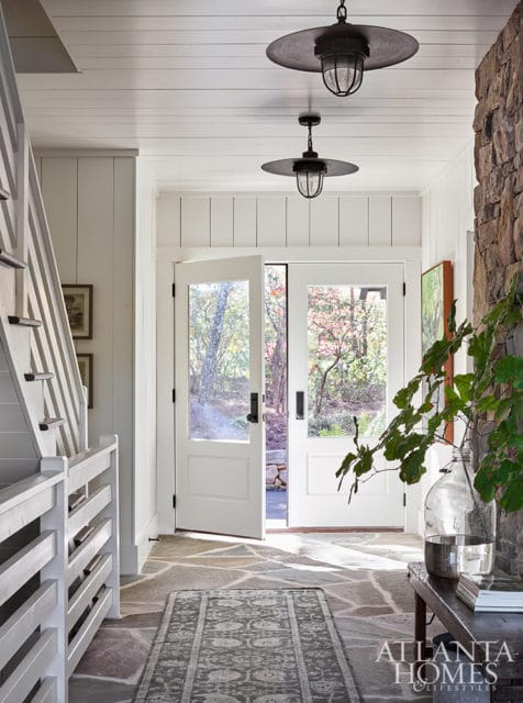 Entryway with stone floor, white paneled walls, double doors, and stone accent wall.