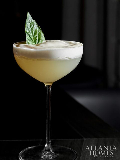 Cocktail with foam and basil leaf in coupe glass